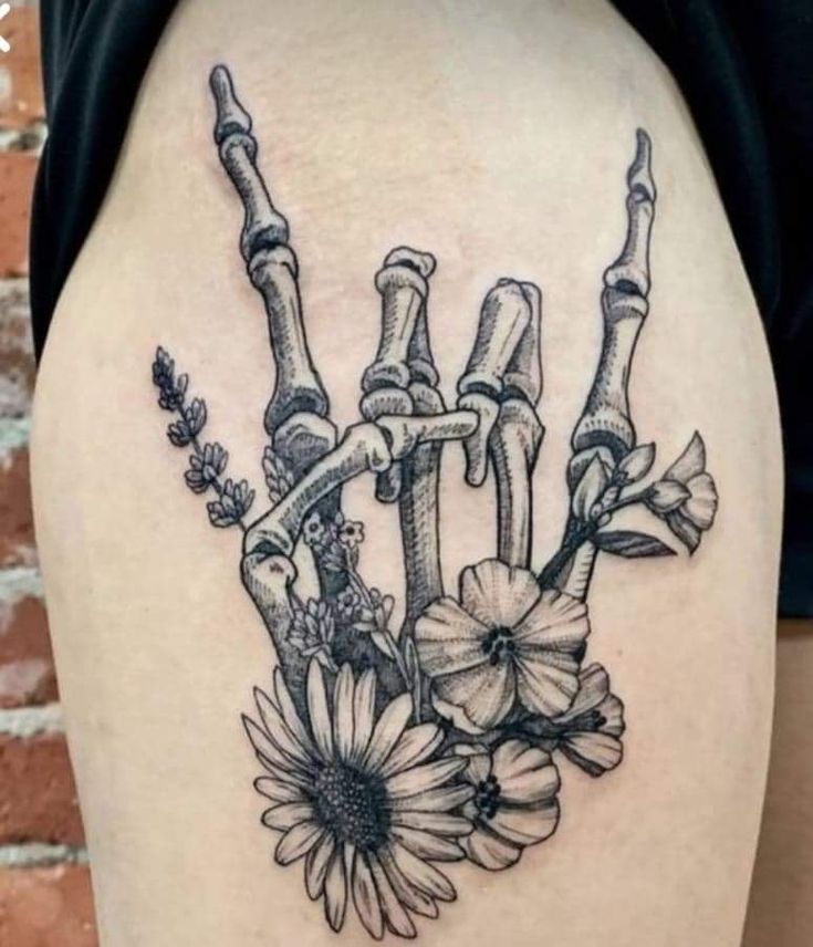 the back of a woman's shoulder with flowers and skeleton bones on her arm