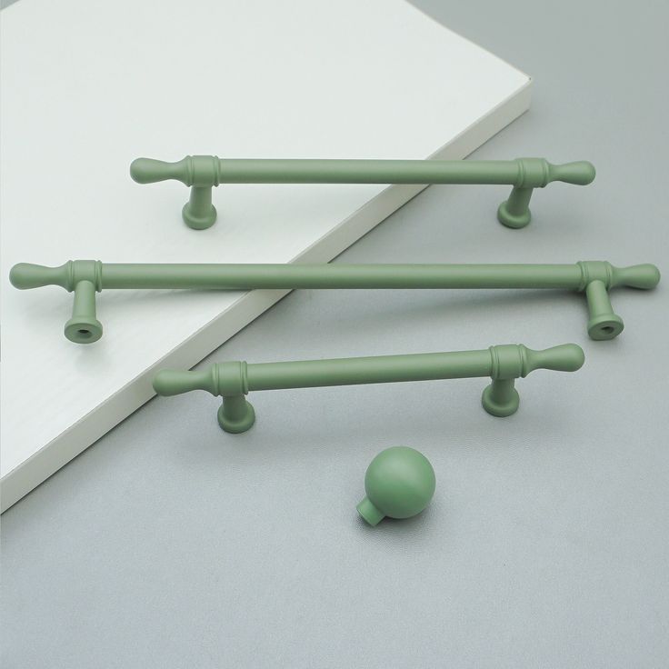 three green handles and knobs on a white surface