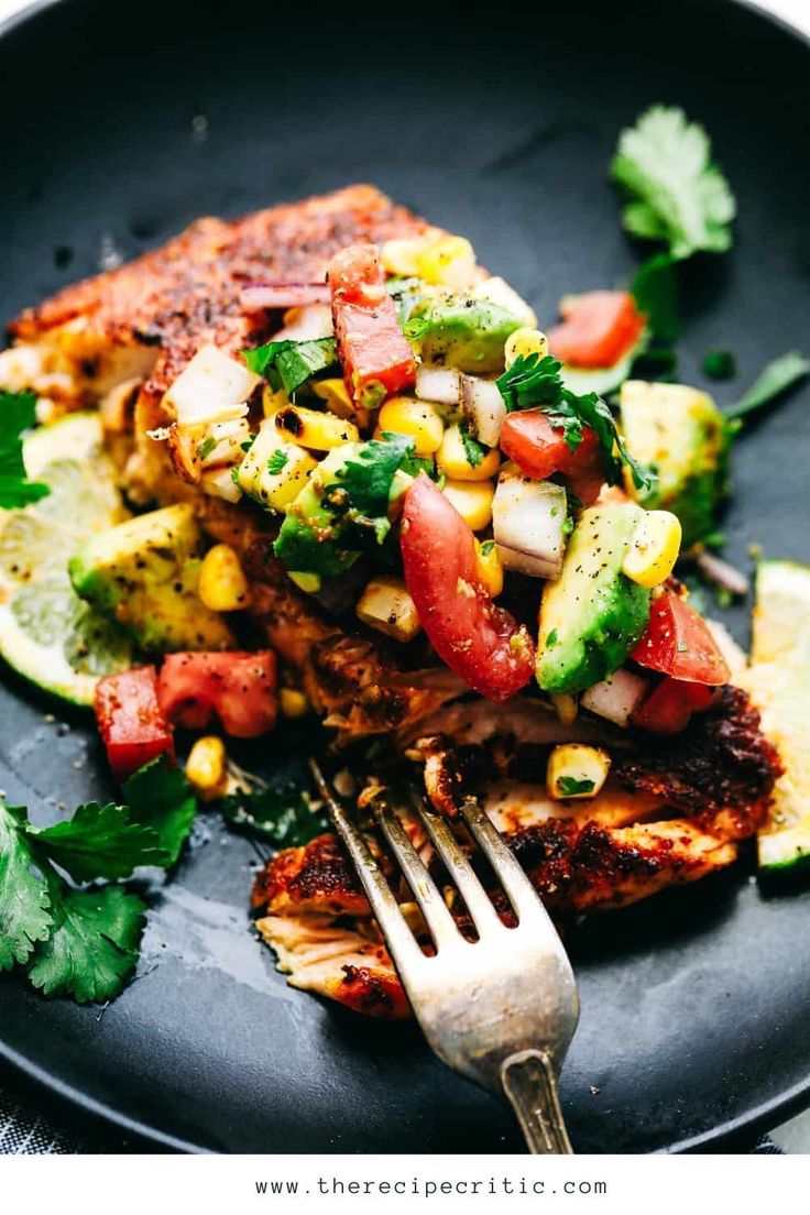 a black plate topped with meat and veggies