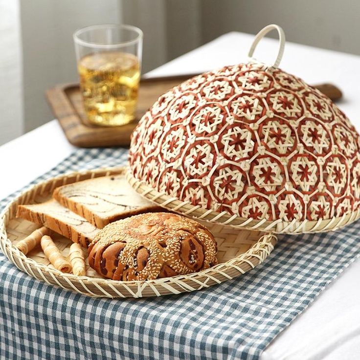 a table topped with bread and pretzels next to a glass of beer on top of a blue checkered table cloth