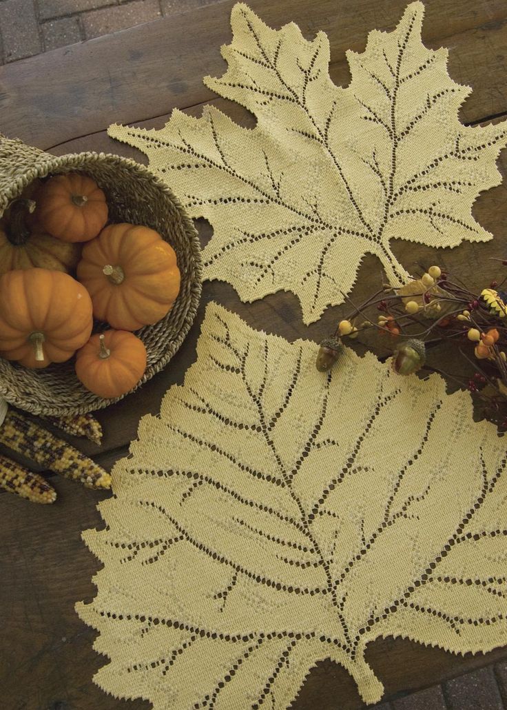 a basket filled with pumpkins sitting on top of a wooden table next to leaves