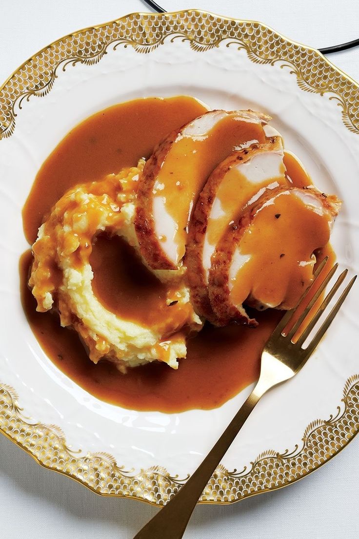 a plate topped with mashed potatoes covered in gravy next to a fork