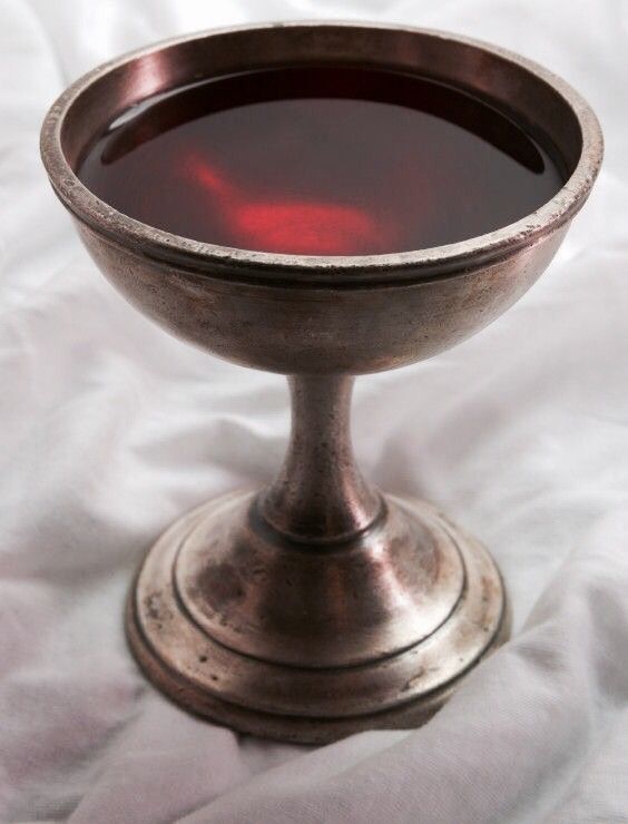 a metal bowl filled with liquid sitting on top of a white cloth covered tablecloth