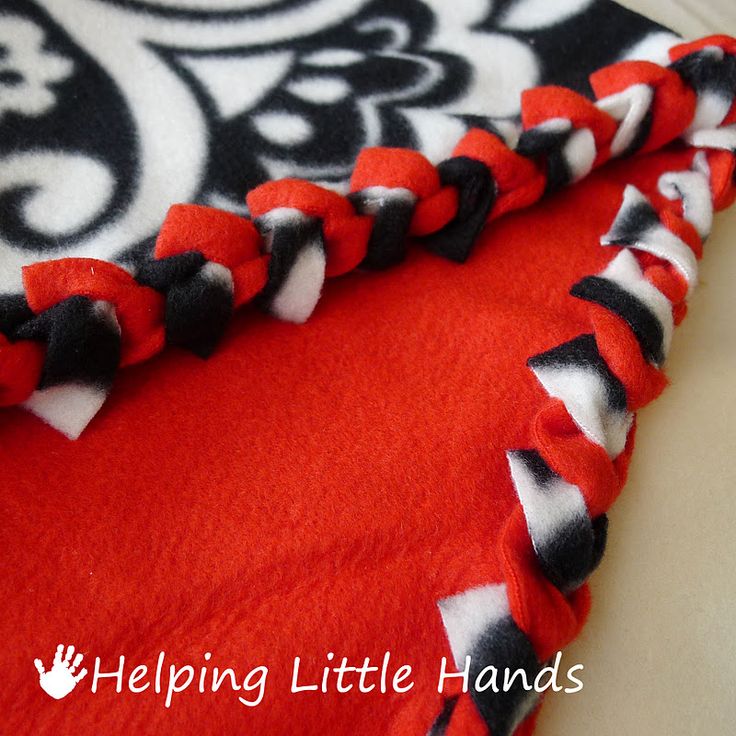 the red and black blanket is laying on top of the white tablecloth with an ornate design