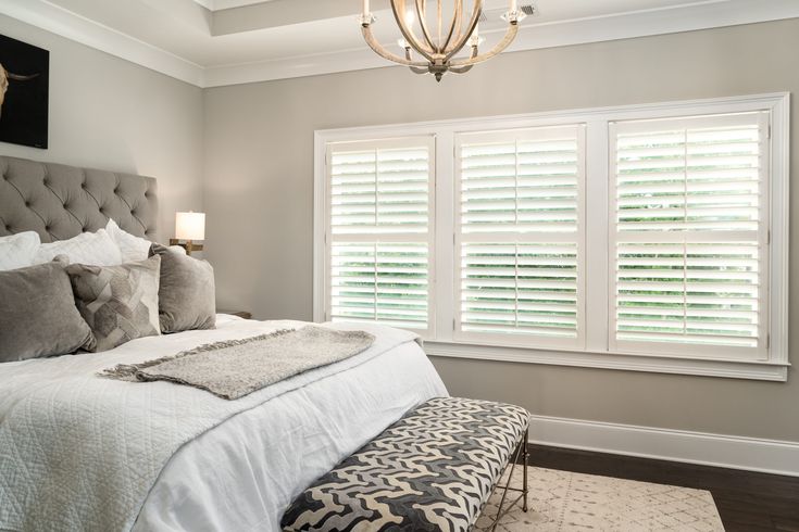 a large bed sitting in a bedroom next to a window with shutters on it