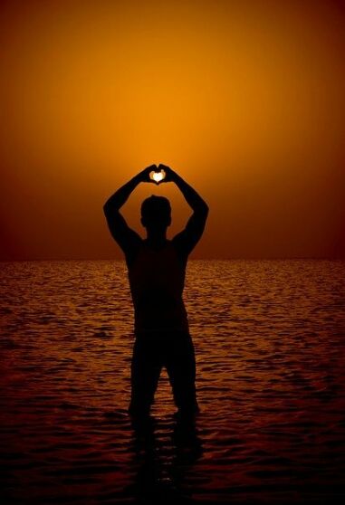 a man standing in the water with his hands on his head at sunset or sunrise