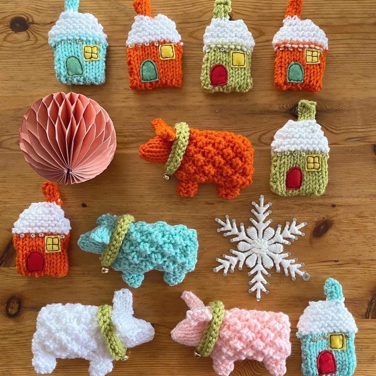 small crocheted houses and farm animals are displayed on a wooden table with ornament