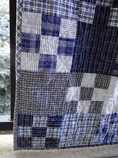 a blue and white patchwork quilt on a window sill in front of a snowy tree