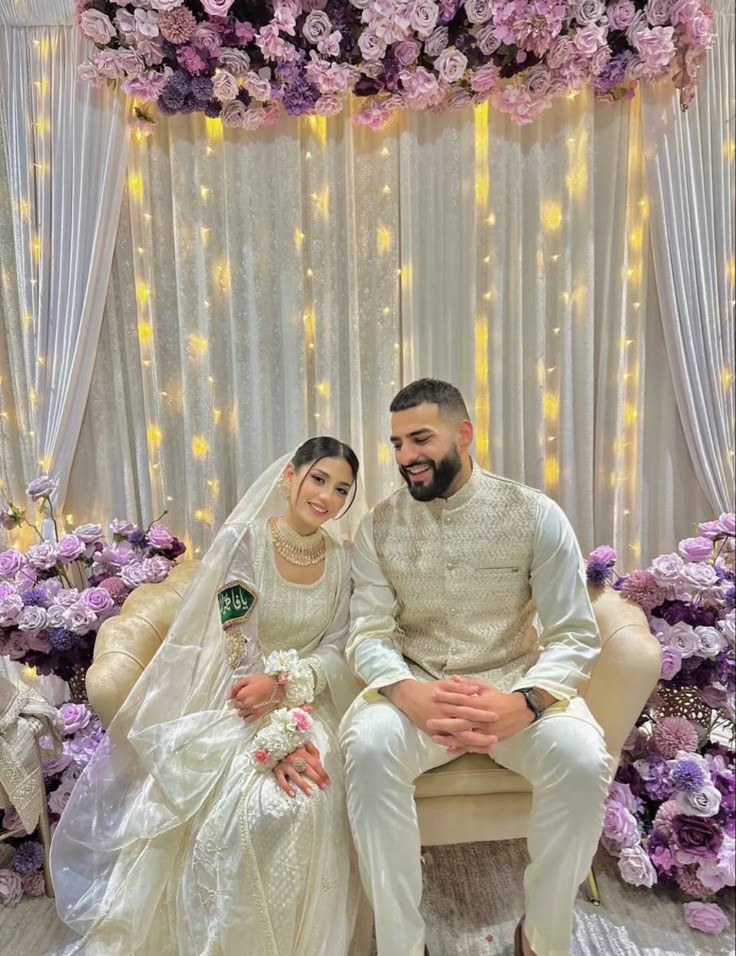 the bride and groom pose for a photo in front of a floral backdrop at their wedding