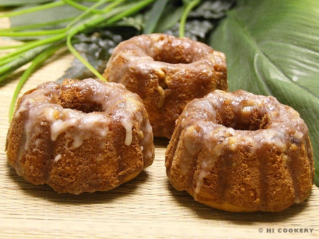 three glazed donuts sitting on top of a wooden cutting board next to green leaves