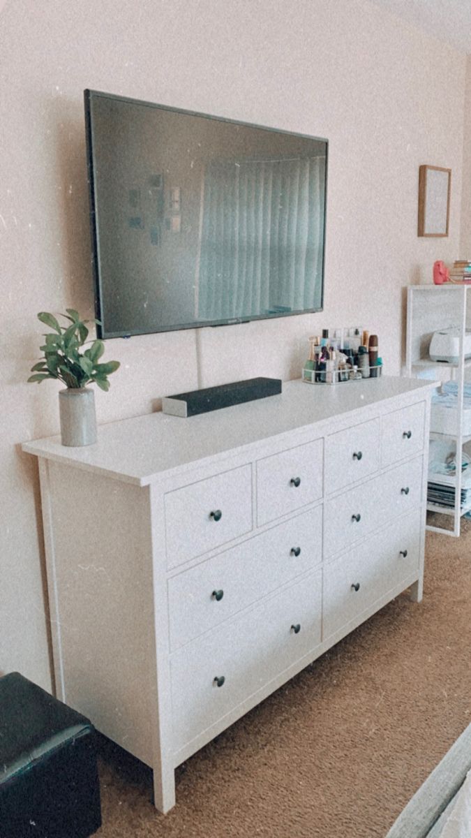 a flat screen tv sitting on top of a white dresser