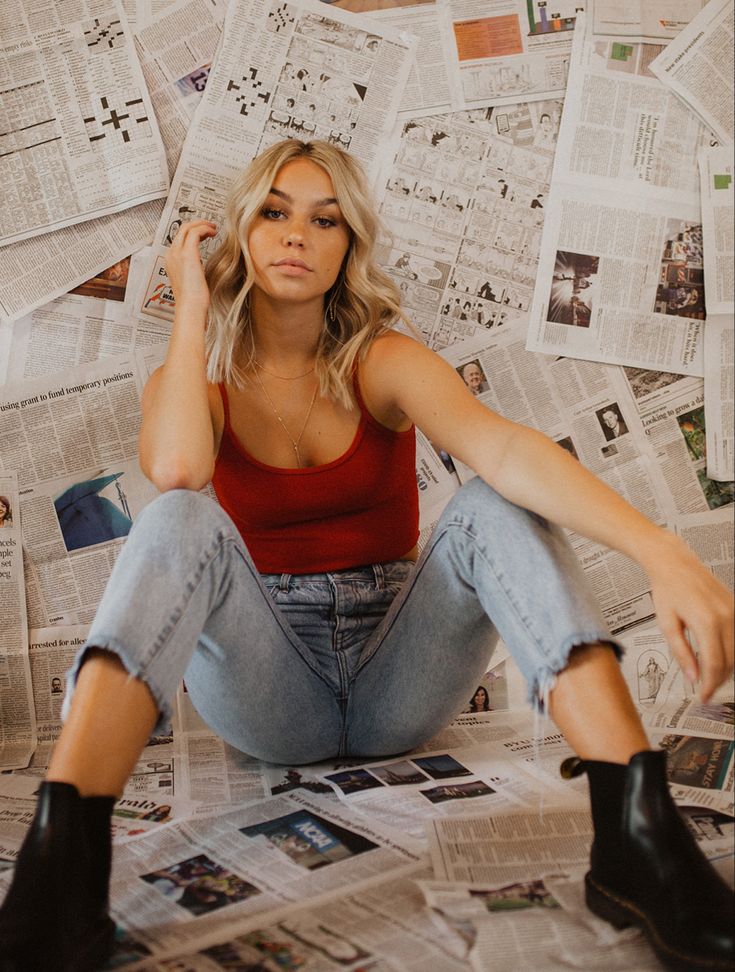 a woman sitting on top of a pile of newspapers