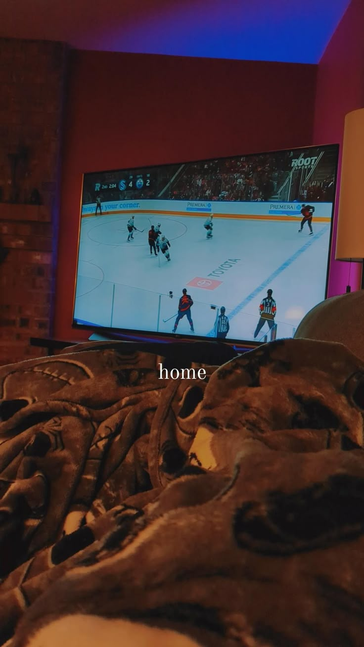 a hockey game on the tv screen in a room with red walls and blue lighting