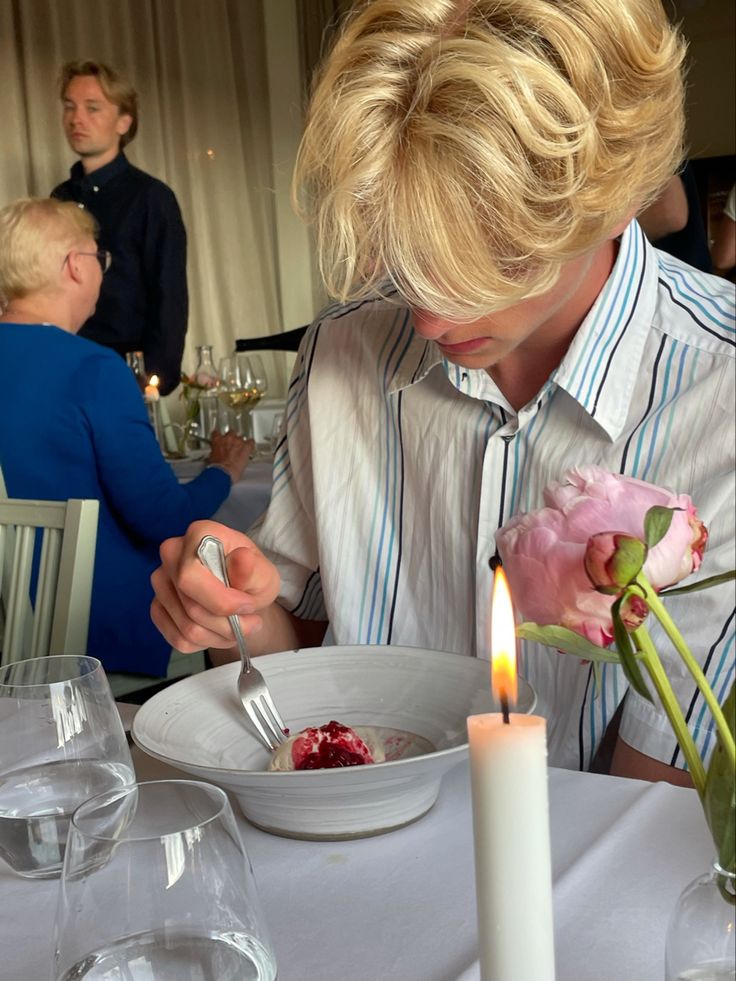 a person sitting at a table with a plate and fork in front of a candle