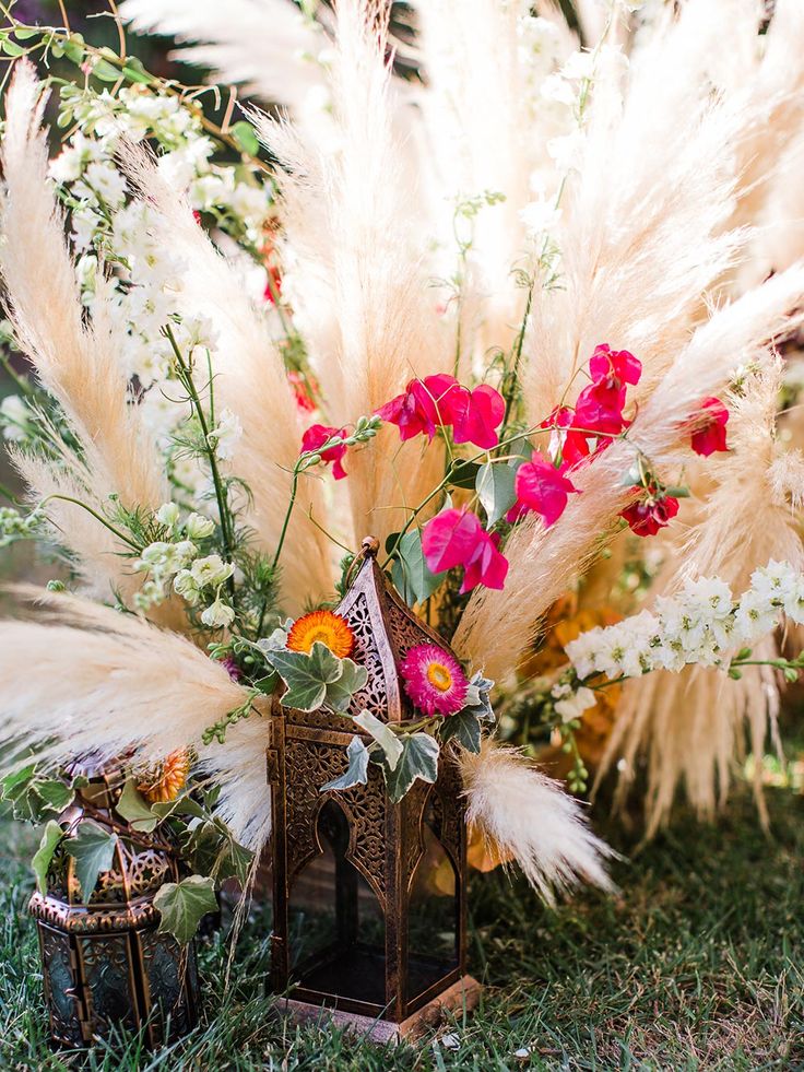 an arrangement of flowers and feathers on the ground in front of a house ornament