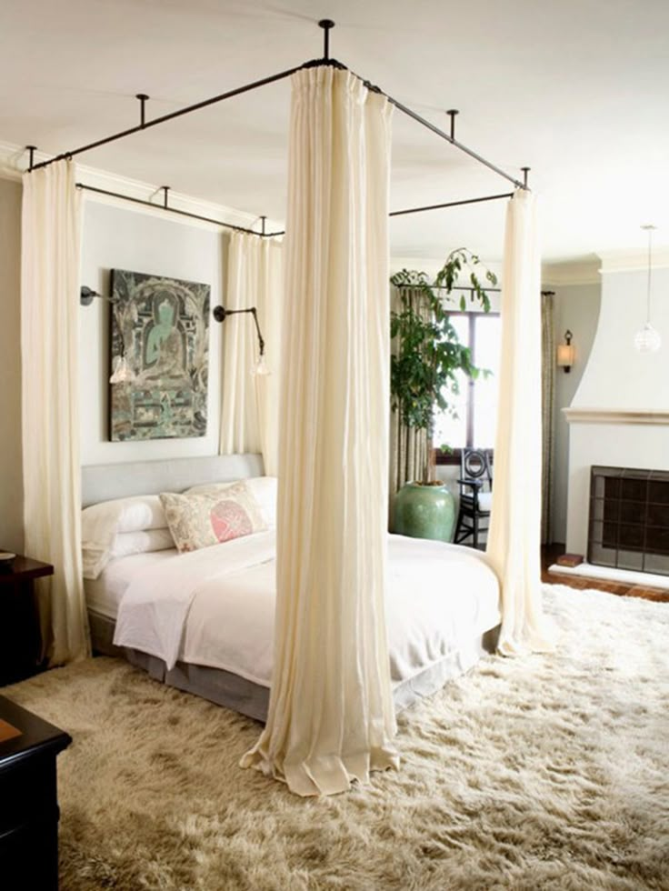 a bedroom with four post bed and white drapes hanging from the ceiling over it