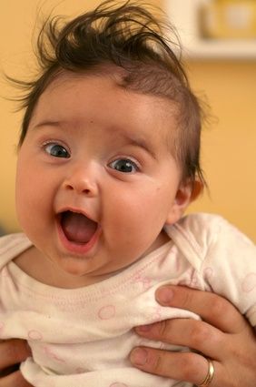 a woman holding a baby in her arms and making a funny face at the camera