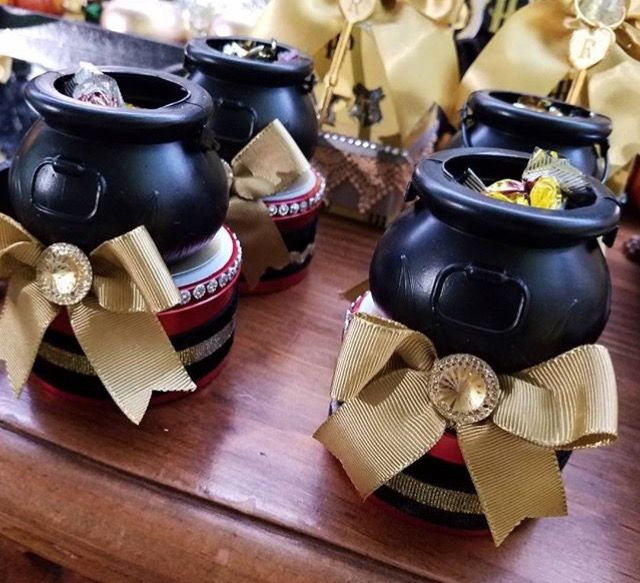 three black pots with bows on them sitting on top of a wooden table next to other items