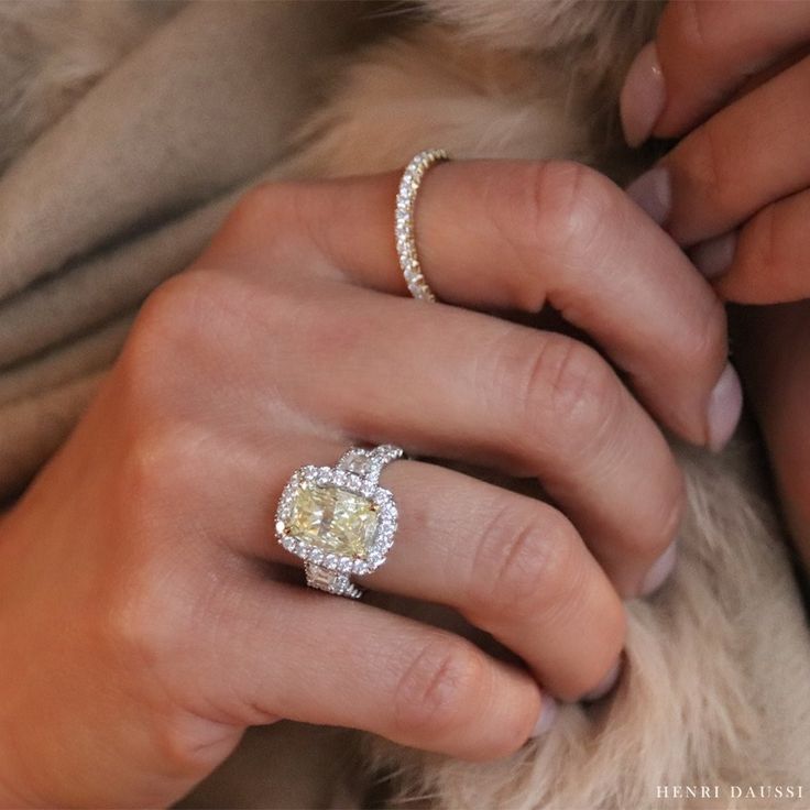 a woman's hand with a yellow diamond ring on top of her left hand