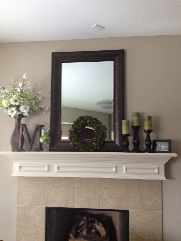 a fireplace with a mirror and flowers on top