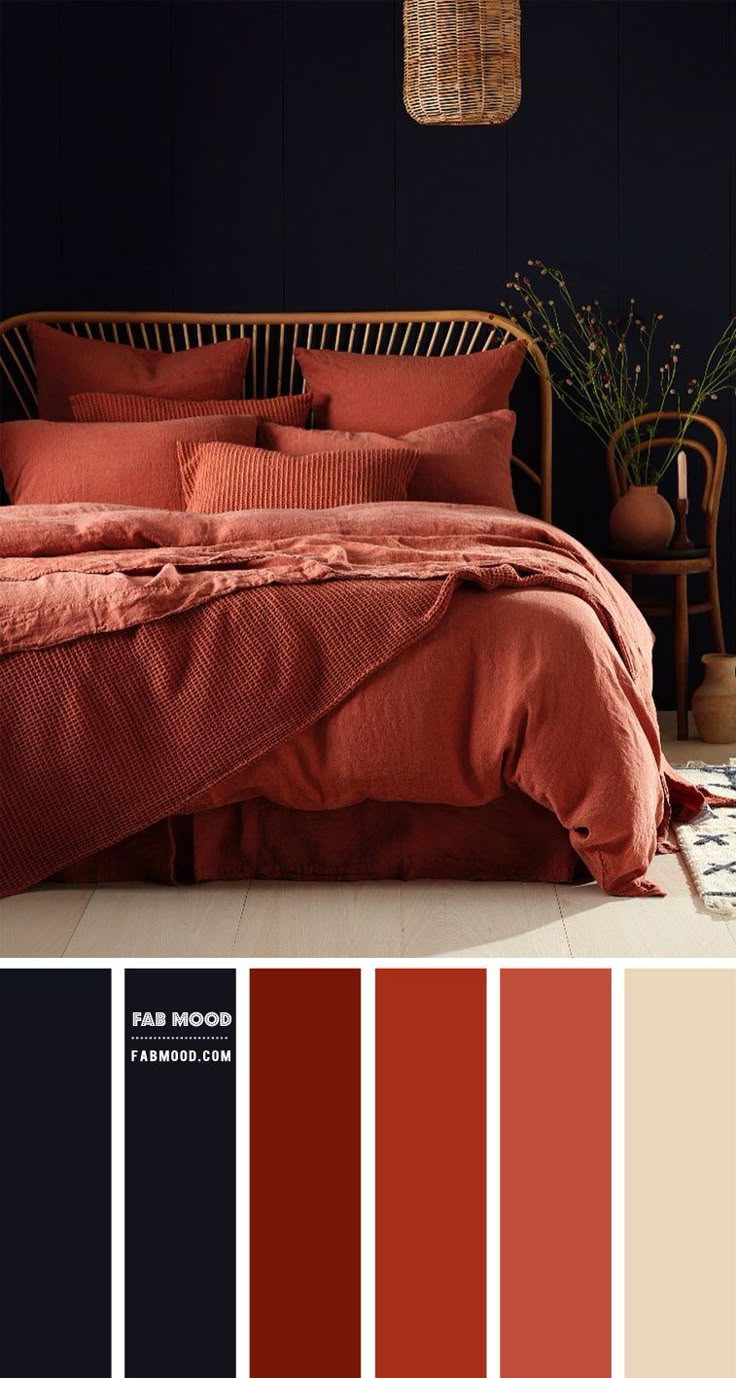 a bed with red sheets and pillows in a room that has dark walls, white flooring and wooden furniture