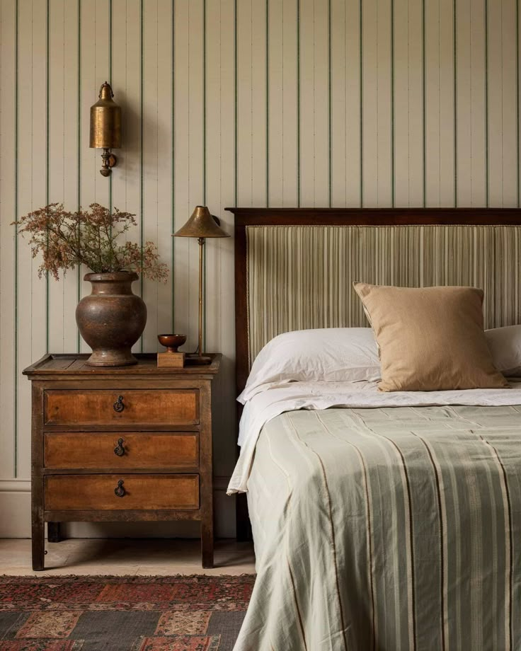 a bed sitting in a bedroom next to a wooden dresser and lamp on top of a rug