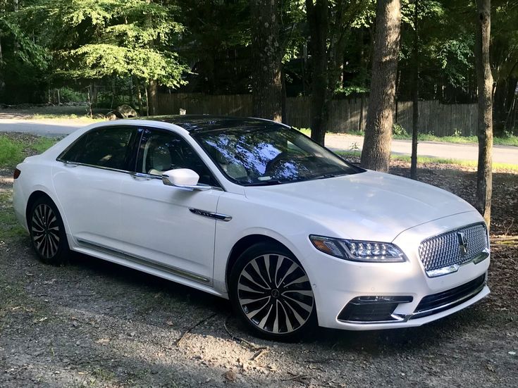 a white car parked in front of some trees