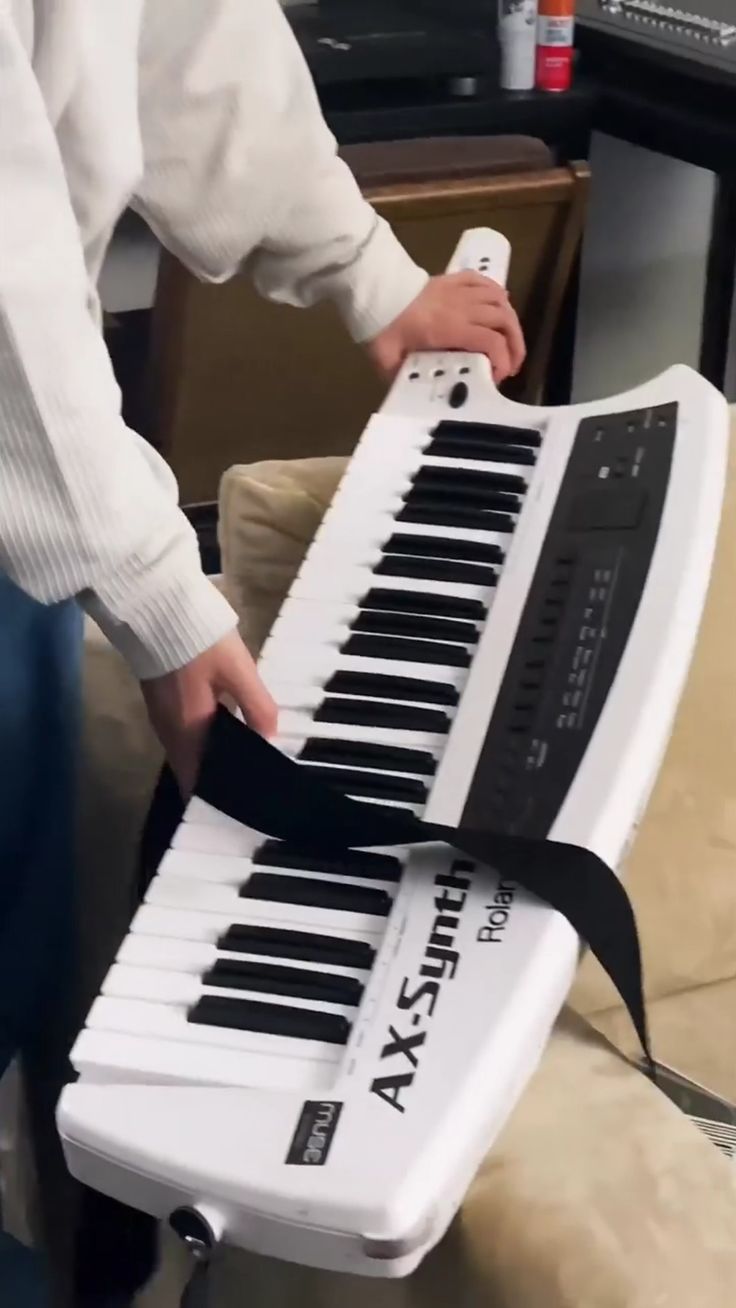 a man is playing an electronic keyboard with a black ribbon on it's neck