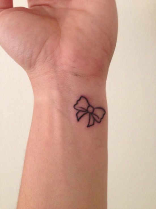 a small black bow tattoo on the wrist