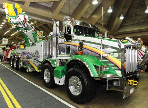 a large semi truck parked inside of a building next to other trucks and people standing around