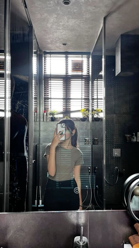 a woman taking a selfie in front of a bathroom mirror