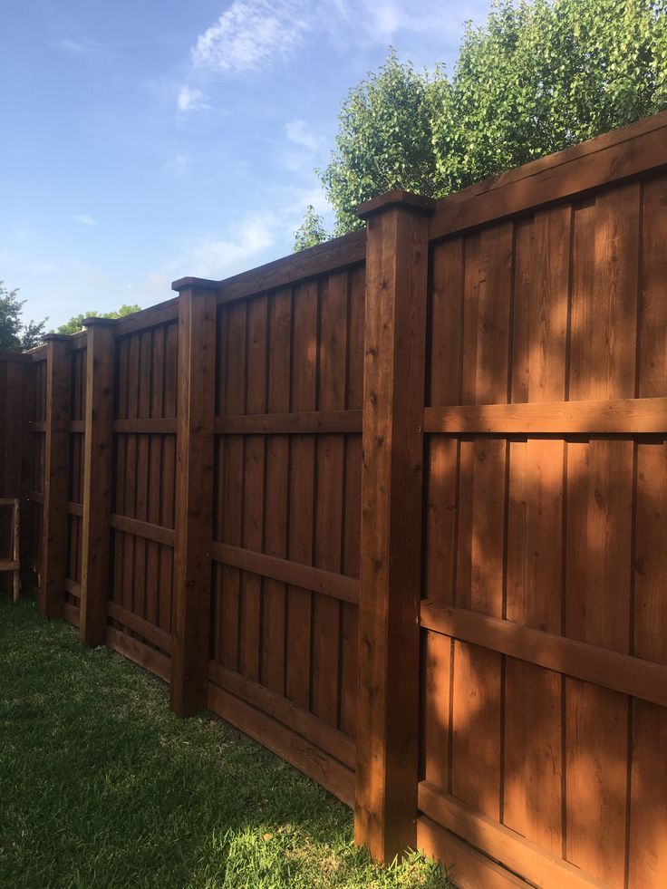 a wooden fence in the grass next to a tree