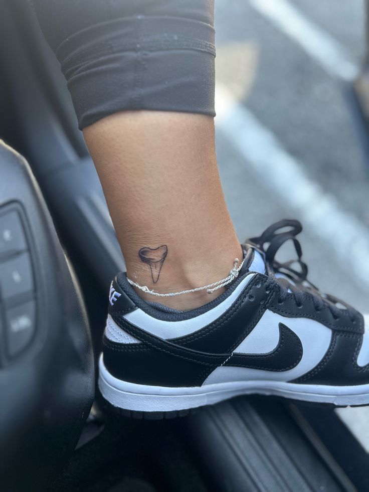 a woman's foot with a small tattoo on her left ankle, sitting on top of a suitcase