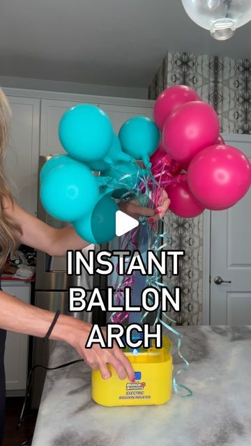 a woman is holding balloons in her hand and pointing to the balloon arch on the counter