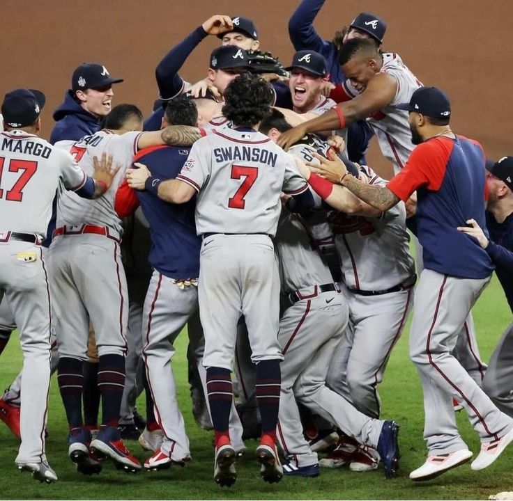 a group of baseball players standing next to each other on top of a lush green field