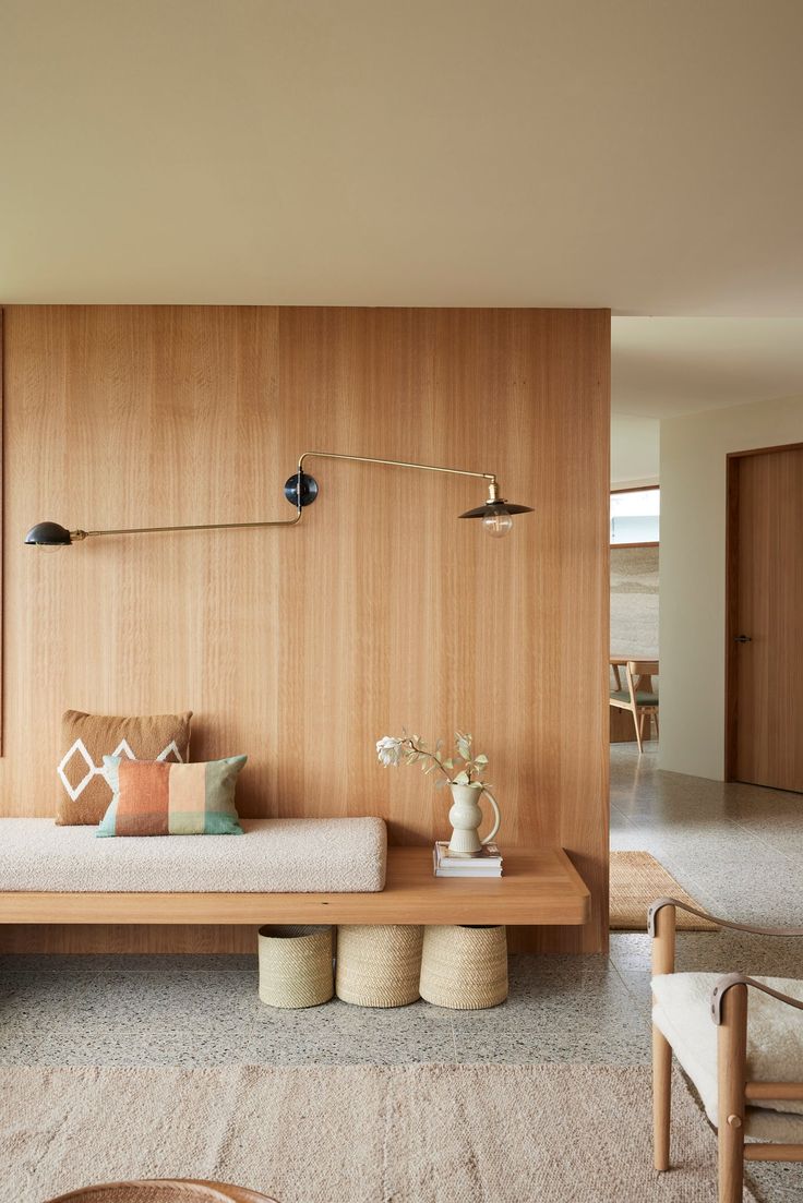 a living room filled with furniture and wooden paneling on the wall next to a window