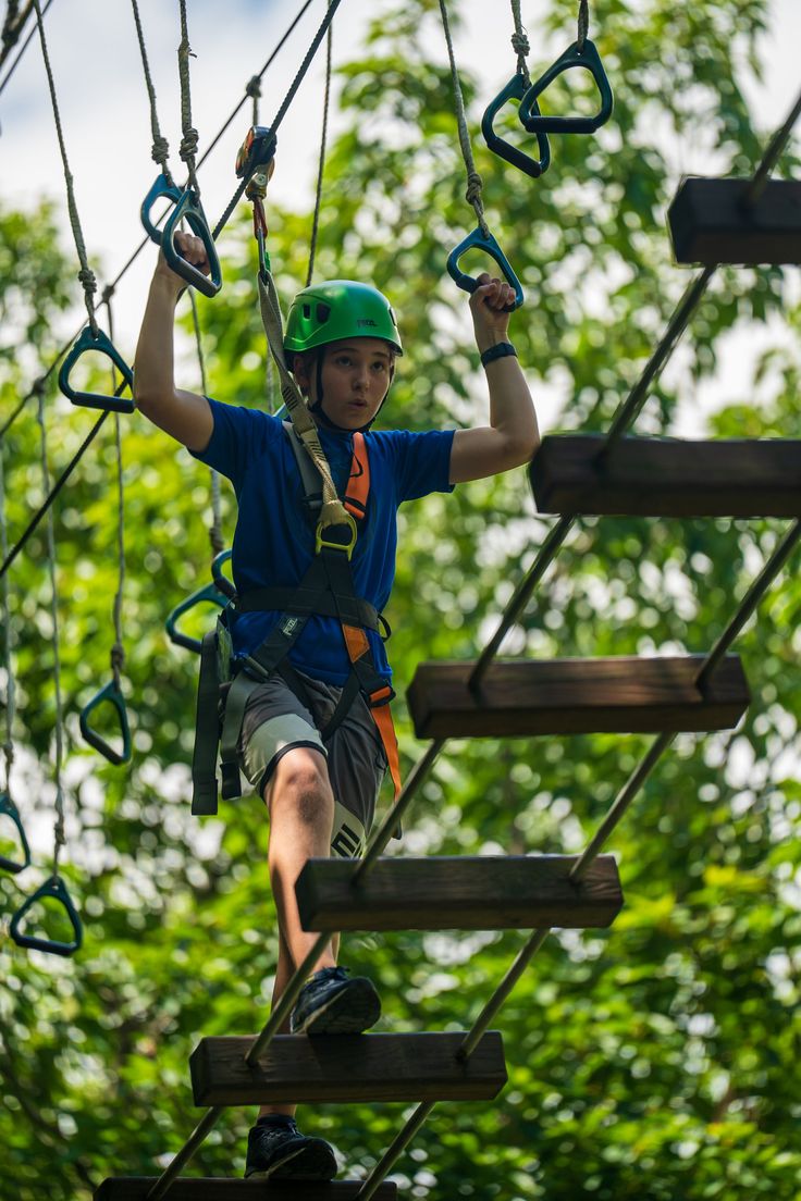 a man on a high ropes course in the forest with safety gear and climbing equipment