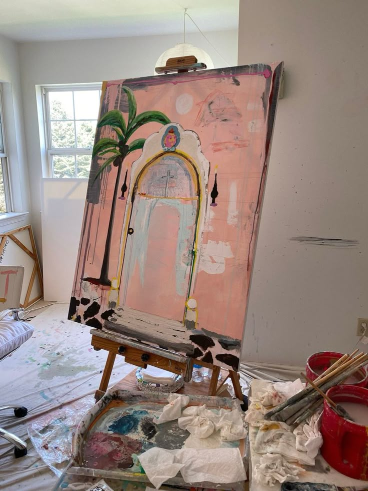 an artist's easel sitting in front of a window with paint on it