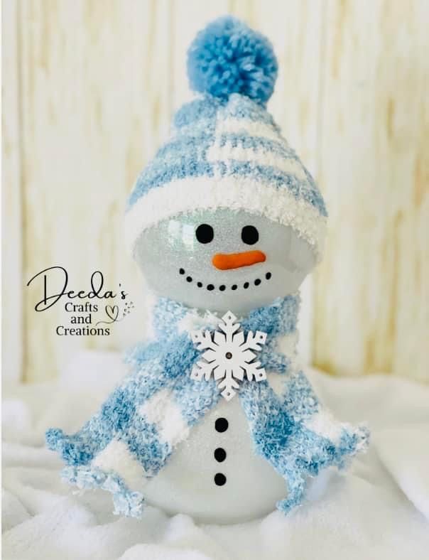 a small snowman with a blue hat and scarf