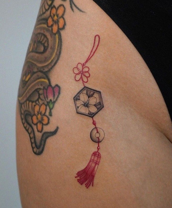 a woman's thigh with tattoos on it and a tatoo hanging from the side