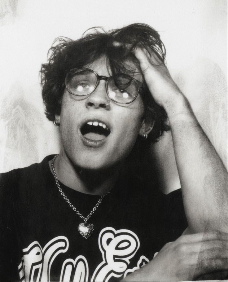 a young man with glasses making a funny face while holding his hands to his head