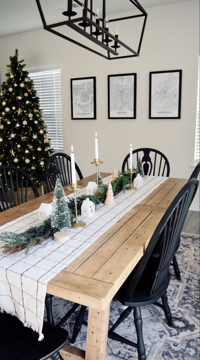 the table is set for christmas dinner with candles on it and pictures hanging above them