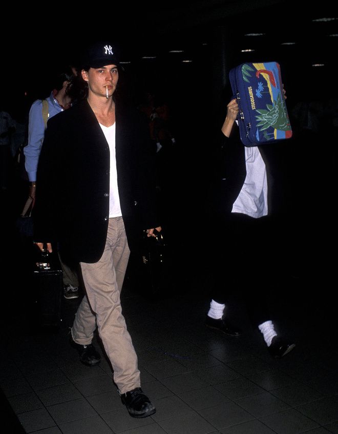 a man walking through an airport holding onto a bag with another person in the background