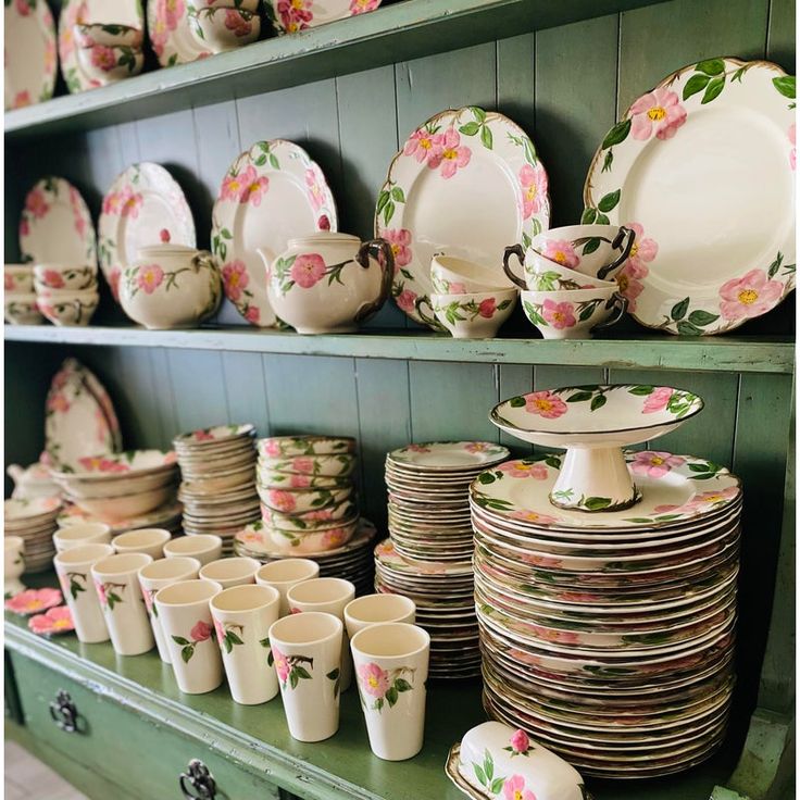 a green shelf filled with lots of plates and cups