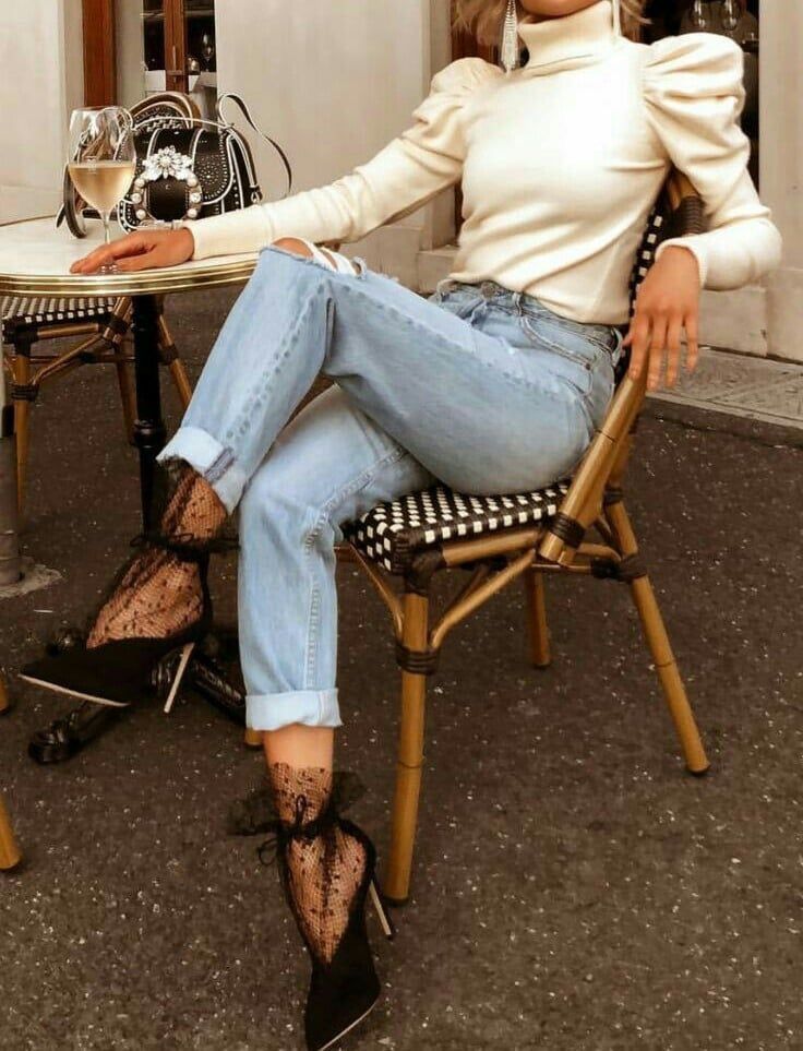 a woman sitting at a table with a glass of wine in her hand and wearing high heels