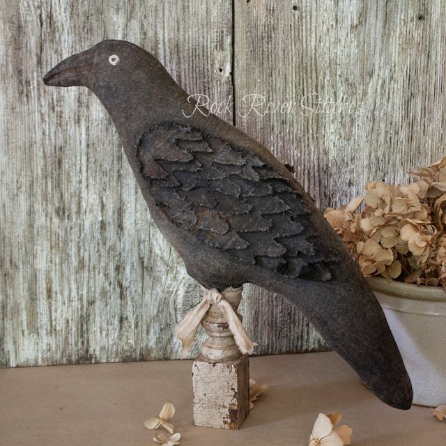 a bird statue sitting on top of a wooden table next to a potted plant