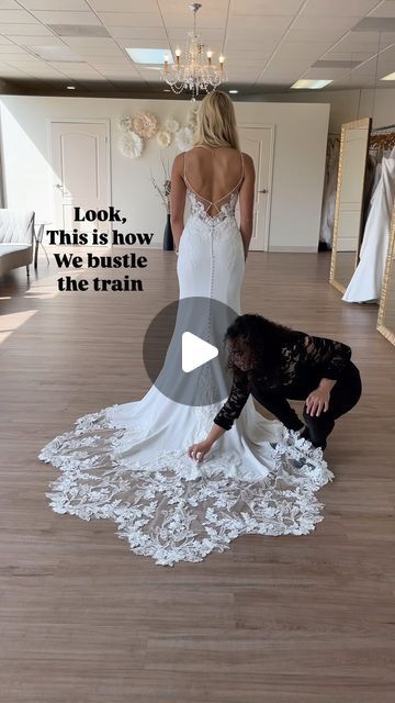 a woman in a wedding dress standing on the floor next to a man who is kneeling down