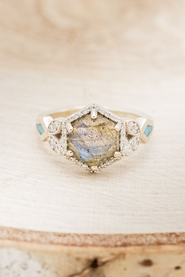 a diamond and labradorite ring sitting on top of a wooden table