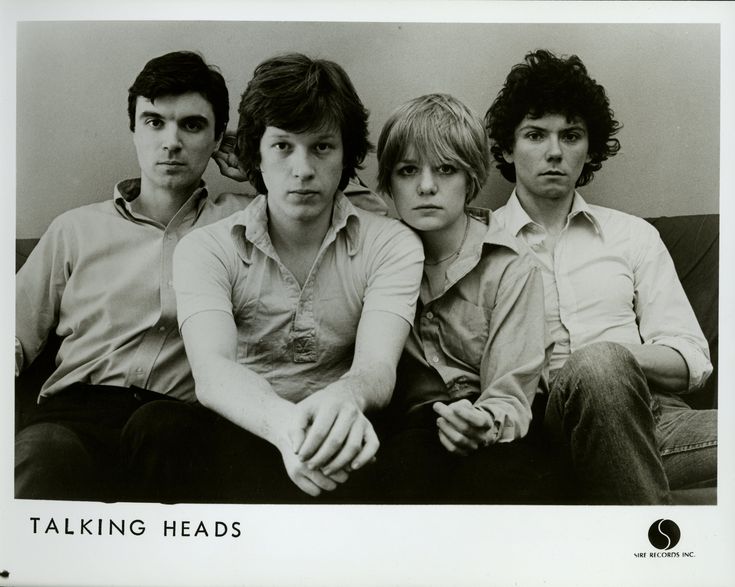 an old photo of four people sitting on a couch with their arms crossed and looking at the camera