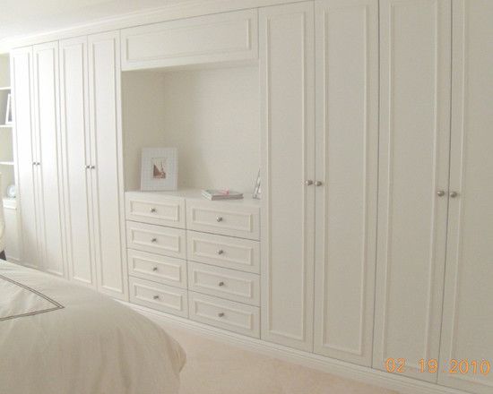 a bedroom with white furniture and carpeted flooring